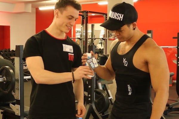 Mann übergibt im Fitnesscenter einen NÖM Proteindrink