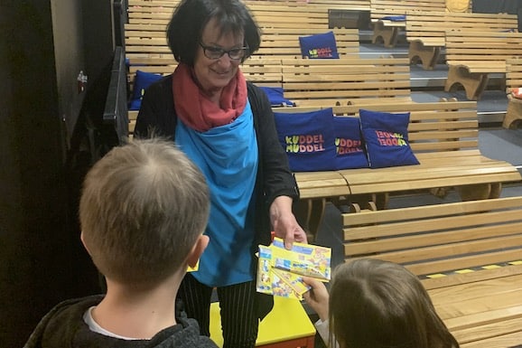 Frau in blauer Schürze verteilt Nesquik Sticks an Kinder