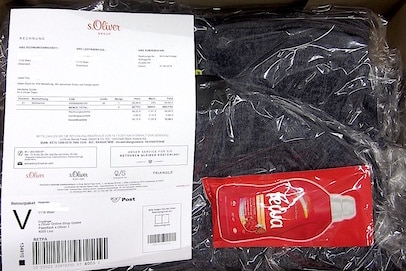 Geöffnetes Paket mit Lieferschein und rotem Produktmuster als Beilage