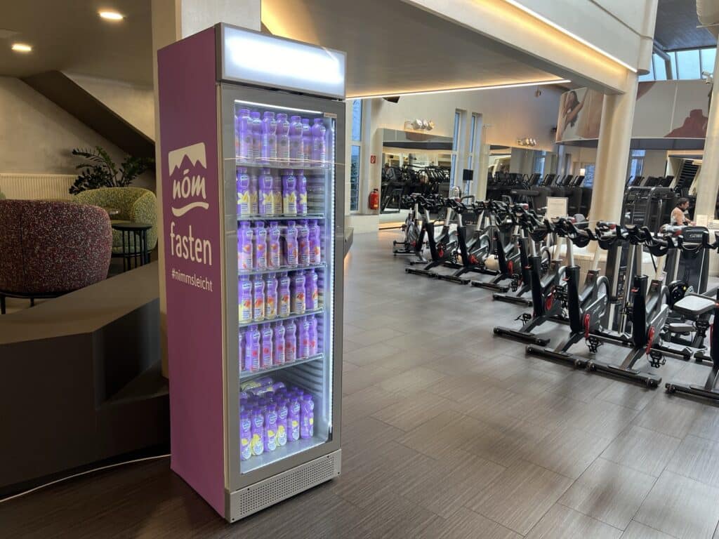 Beleuchteter NÖM Kühlschrank im Fitnessstudio mit Produktproben