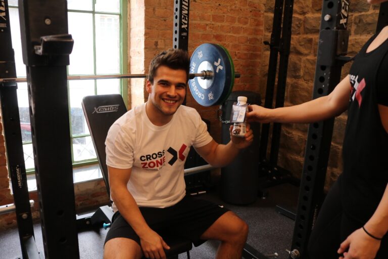 Sportler erhält im CrossZone Fitnessstudio einen Proteindrink, Sampling über Freudebringer