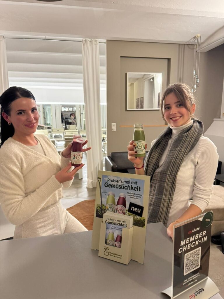 Zwei Frauen mit Innocent Smoothies beim myclubs Check-in, Sampling über Freudebringer
