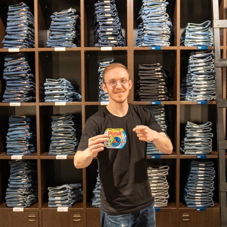 Mann in einem Jeansgeschäft hält eine Persil Produktprobe