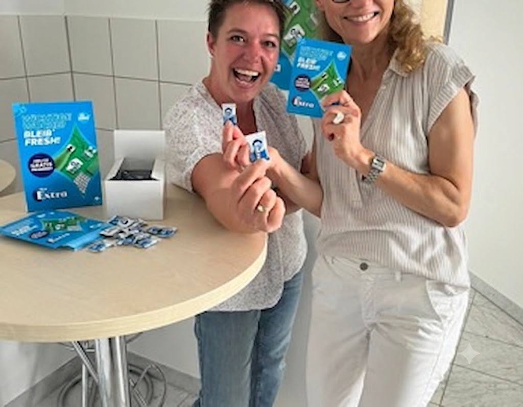 Zwei Frauen halten Produktpackungen an einem weißen Tisch