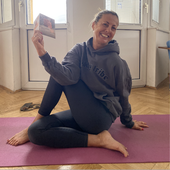 Frau macht Yoga auf einer rosa Matte und hält eine Produktprobe